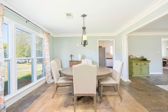 dining area featuring concrete flooring, a wealth of natural light, ornamental molding, and decorative columns