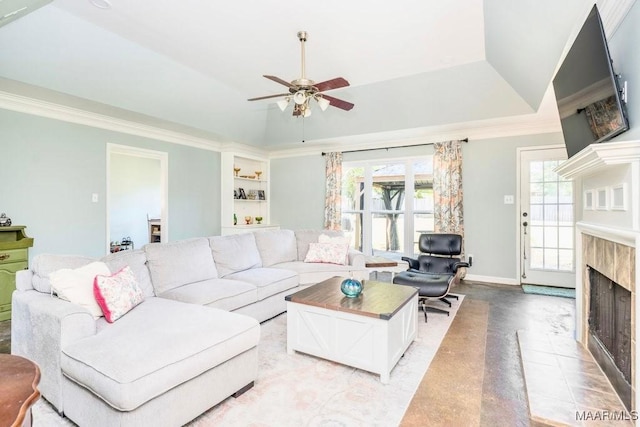 living room featuring a tray ceiling, crown molding, built in features, and ceiling fan