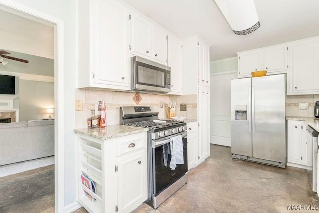 kitchen featuring tasteful backsplash, white cabinets, light stone counters, ceiling fan, and stainless steel appliances