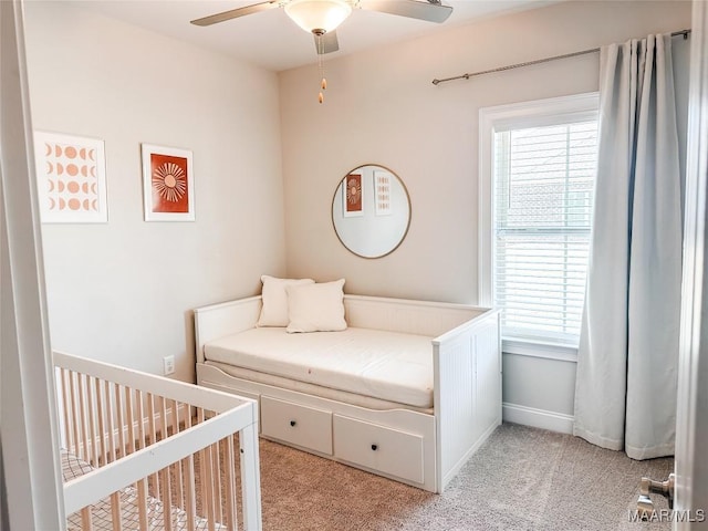 bedroom featuring ceiling fan, light carpet, a nursery area, and multiple windows