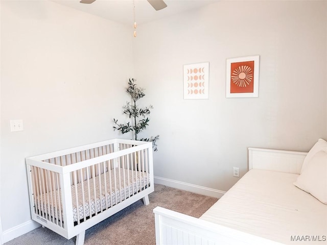 carpeted bedroom featuring ceiling fan, a crib, and baseboards