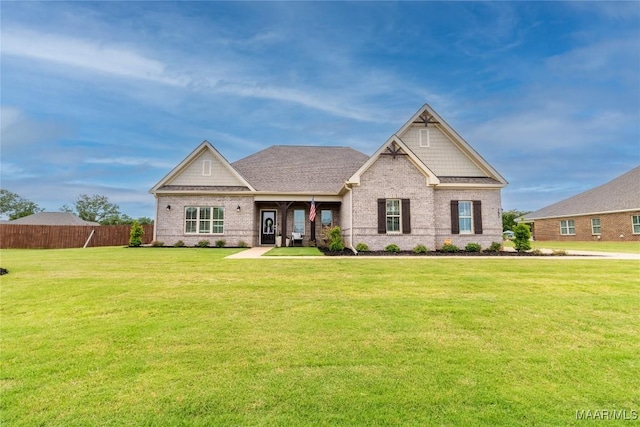 craftsman-style home featuring a front yard, brick siding, and fence