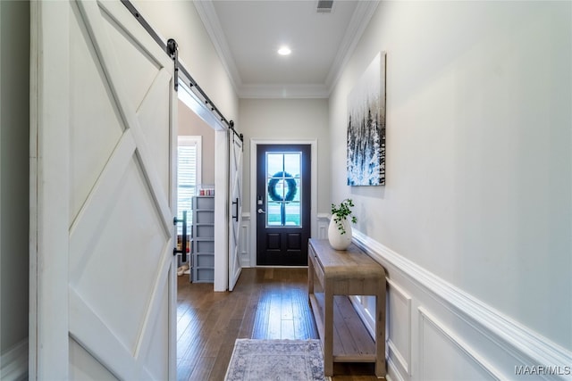 entryway with ornamental molding, a barn door, and dark hardwood / wood-style flooring