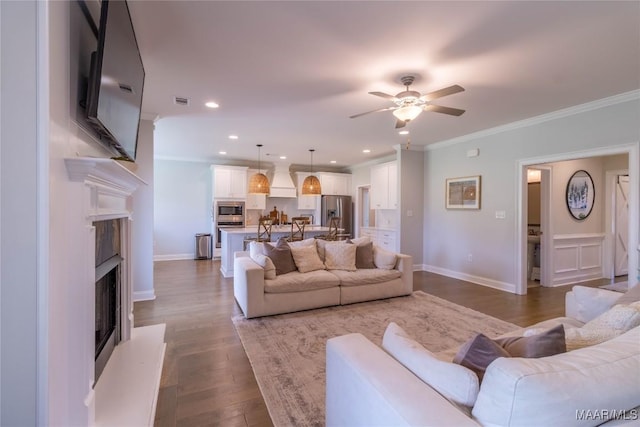 living area featuring recessed lighting, a fireplace with raised hearth, crown molding, a ceiling fan, and wood finished floors
