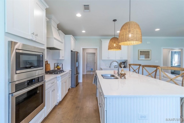 kitchen with sink, white cabinetry, a kitchen island with sink, hanging light fixtures, and stainless steel appliances