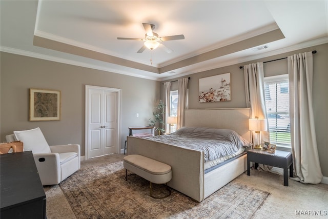 bedroom with ceiling fan, carpet, a tray ceiling, and ornamental molding