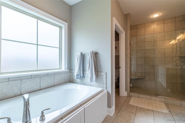 bathroom with independent shower and bath, plenty of natural light, tile patterned floors, and toilet