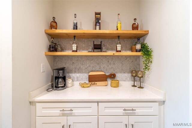 bar featuring light stone counters and white cabinets