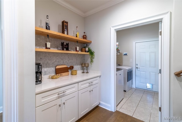 bar featuring ornamental molding, white cabinetry, washing machine and clothes dryer, and light tile patterned floors