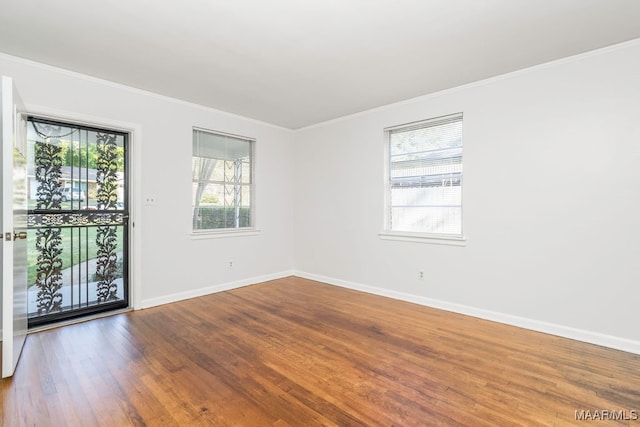 unfurnished room with hardwood / wood-style floors, crown molding, and plenty of natural light