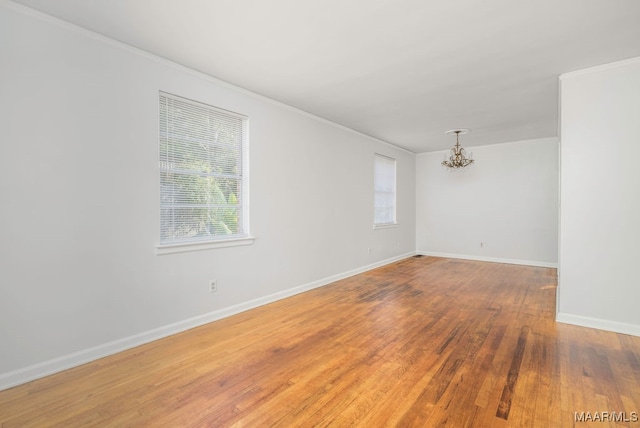 spare room with crown molding, hardwood / wood-style flooring, and an inviting chandelier