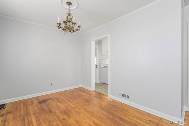 spare room featuring ornamental molding, washer / clothes dryer, a chandelier, and hardwood / wood-style floors