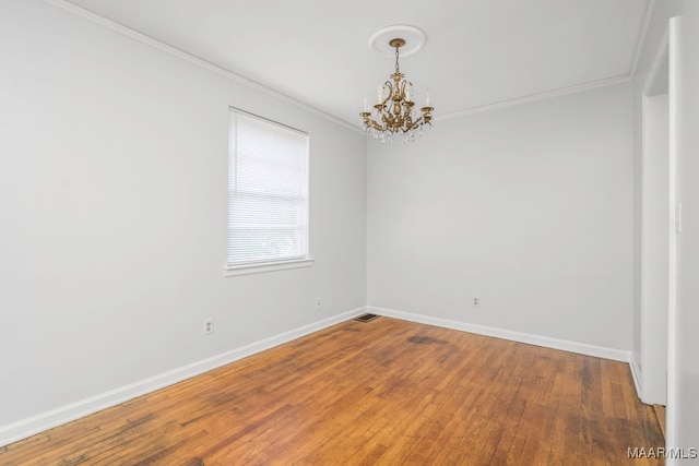 empty room with ornamental molding, hardwood / wood-style floors, and a chandelier