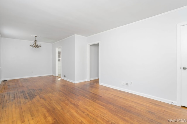 spare room featuring crown molding, a notable chandelier, and wood-type flooring