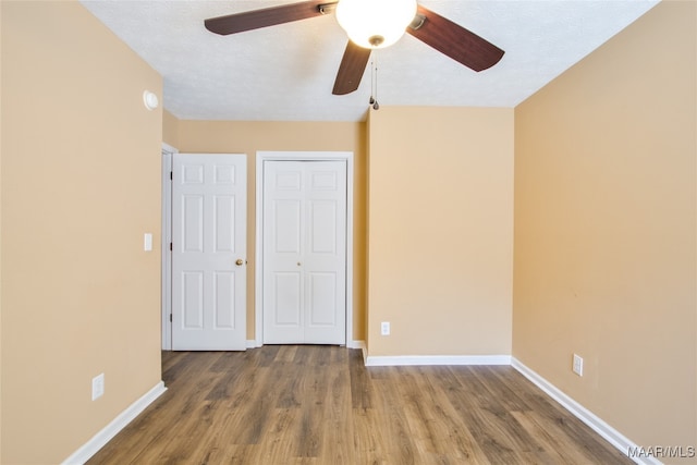 unfurnished bedroom with a closet, ceiling fan, hardwood / wood-style flooring, and a textured ceiling