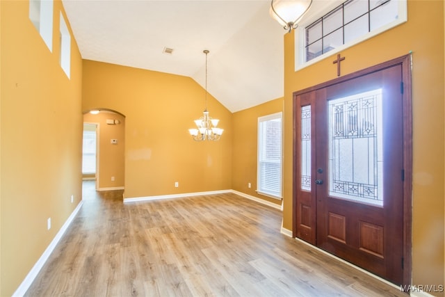 foyer entrance featuring a notable chandelier, high vaulted ceiling, and light wood-type flooring