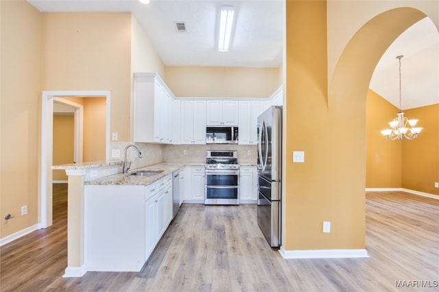 kitchen featuring sink, hanging light fixtures, light hardwood / wood-style floors, stainless steel appliances, and white cabinets