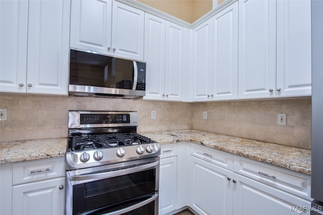 kitchen featuring white cabinetry, light stone counters, appliances with stainless steel finishes, and decorative backsplash