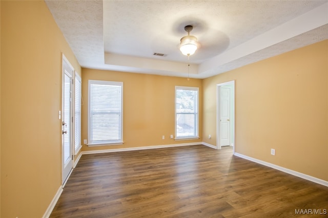 spare room featuring a textured ceiling, ceiling fan, a tray ceiling, and dark hardwood / wood-style flooring