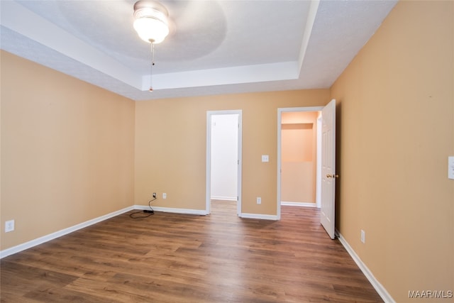 spare room featuring ceiling fan, a raised ceiling, and dark hardwood / wood-style flooring