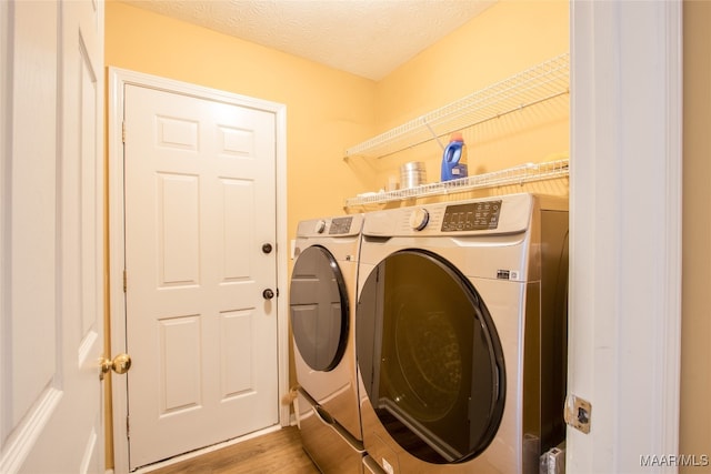 laundry area featuring a textured ceiling, separate washer and dryer, and light wood-type flooring