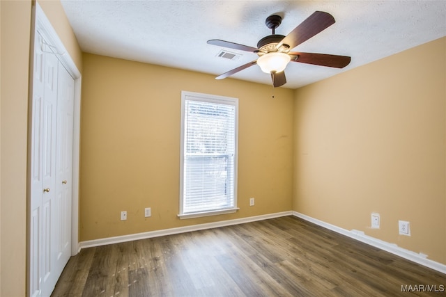 empty room with dark hardwood / wood-style floors, a textured ceiling, and ceiling fan