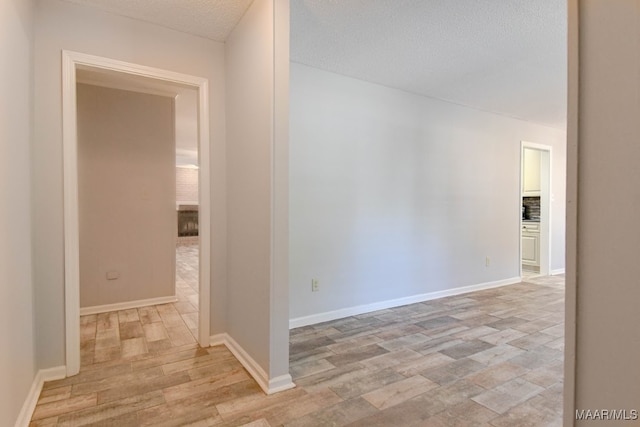 hallway with light hardwood / wood-style flooring and a textured ceiling