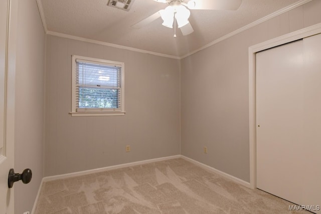 carpeted spare room featuring crown molding, a textured ceiling, and ceiling fan