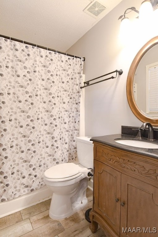 bathroom with toilet, wood-type flooring, vanity, a textured ceiling, and walk in shower