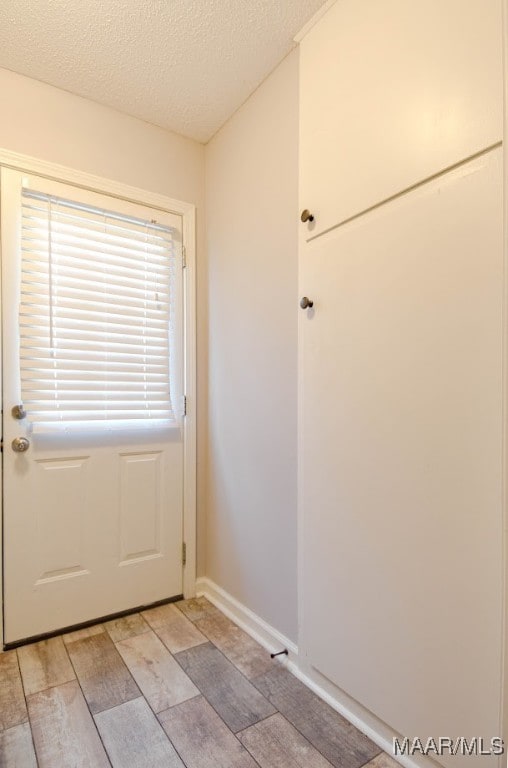 doorway to outside featuring light hardwood / wood-style floors and a textured ceiling