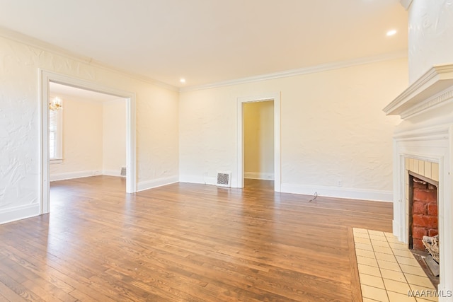 unfurnished living room featuring light hardwood / wood-style floors, ornamental molding, and a tile fireplace