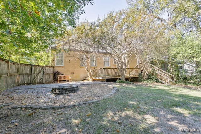view of yard with a fire pit, a wooden deck, stairway, and fence