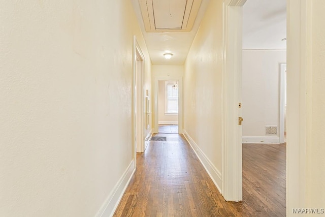 corridor featuring baseboards, attic access, dark wood finished floors, and visible vents