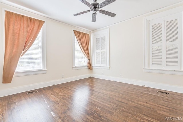empty room with a ceiling fan, visible vents, and wood finished floors