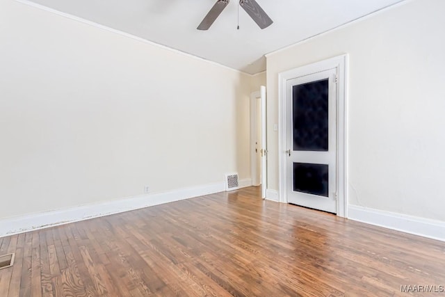 empty room featuring crown molding, ceiling fan, baseboards, wood finished floors, and visible vents