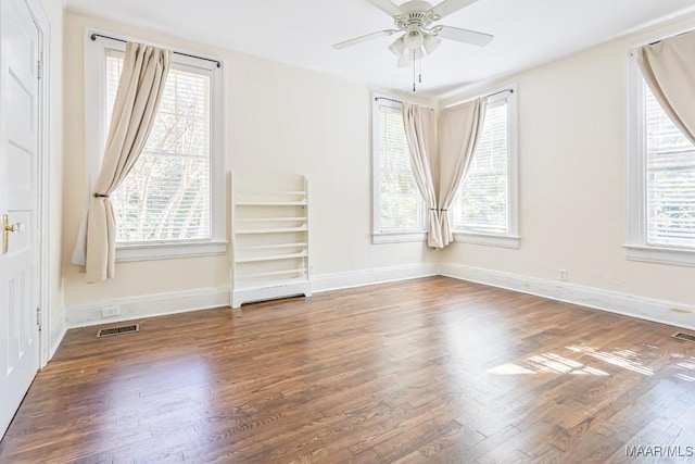 spare room featuring visible vents, a ceiling fan, baseboards, and wood finished floors