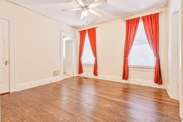 unfurnished room featuring a ceiling fan, visible vents, a healthy amount of sunlight, and wood finished floors