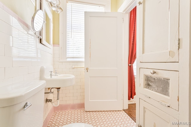 bathroom with tile walls, sink, toilet, and tile patterned flooring