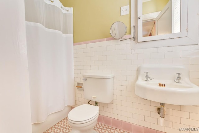 full bathroom with a sink, toilet, tile patterned floors, a wainscoted wall, and tile walls