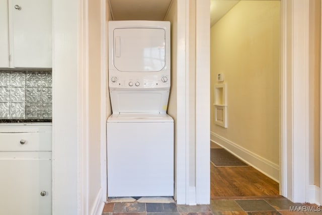 clothes washing area featuring stacked washer and dryer and dark wood-type flooring