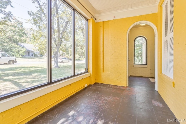 spare room with crown molding, arched walkways, and a textured wall