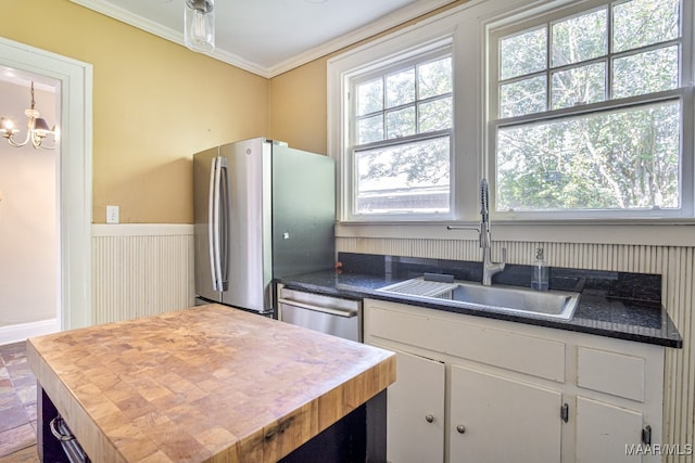 kitchen featuring appliances with stainless steel finishes, sink, white cabinets, ornamental molding, and a chandelier