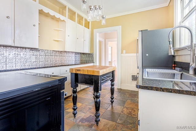 kitchen featuring backsplash, white cabinetry, pendant lighting, crown molding, and sink