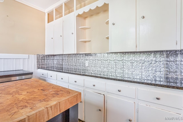 kitchen with decorative backsplash, crown molding, white cabinets, and butcher block countertops