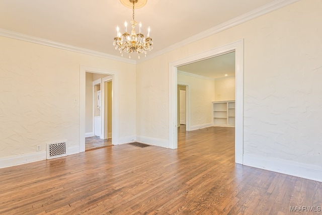 empty room featuring ornamental molding, hardwood / wood-style floors, and a chandelier