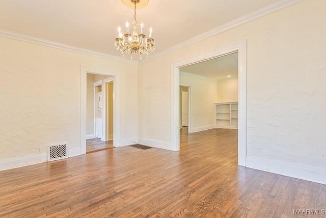unfurnished dining area featuring visible vents, ornamental molding, wood finished floors, baseboards, and a notable chandelier