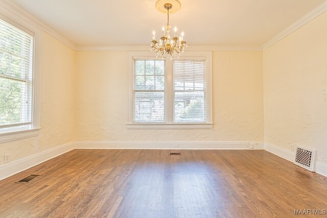 unfurnished room featuring crown molding, hardwood / wood-style floors, and a chandelier