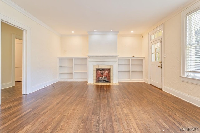 unfurnished living room featuring a tiled fireplace, baseboards, ornamental molding, and wood finished floors