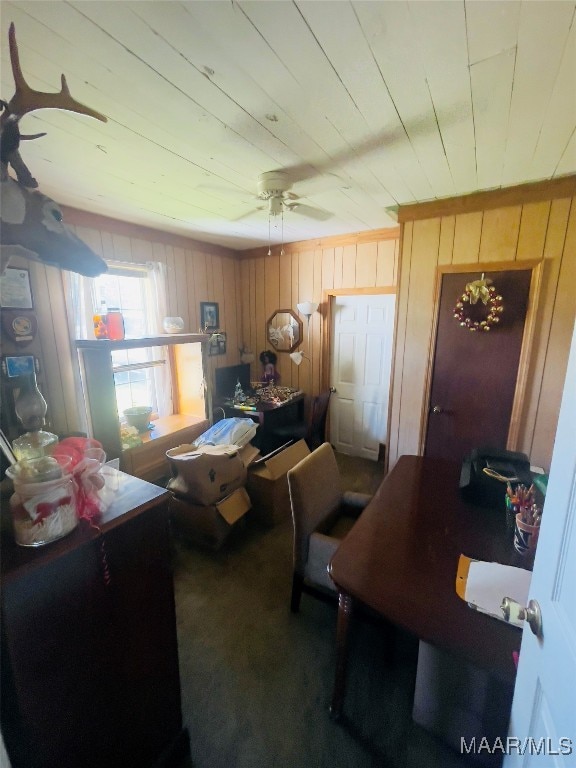 home office with wood walls, ceiling fan, and carpet floors