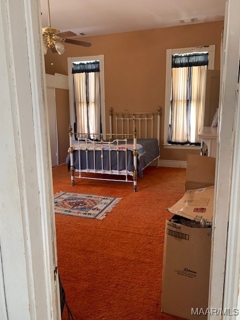 carpeted bedroom with multiple windows and ceiling fan